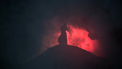 Christian Monk in a Tunic Leans on a Cross Under a Storm