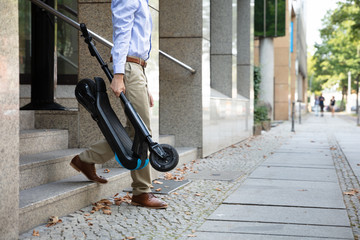 Man Carrying E-Scooter From Work
