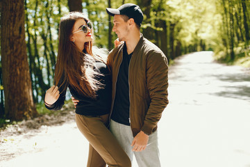 A stylish and bright love couple walks in the sunny forest