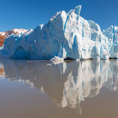 Ice peak of the Grey Glacier with a reflection in the Grey lake and the Andes mountain range in the...