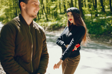 A stylish and bright love couple walks in the sunny forest