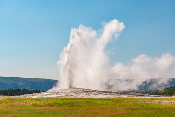 The Old Faithful geyser having an eruption on a bright summer day, Yellowstone National Park,...