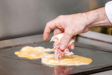 Chef cooking delicious Omelette with ham and cheese .