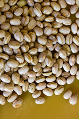 Dry and uncooked brown beans with a warm and yellow background