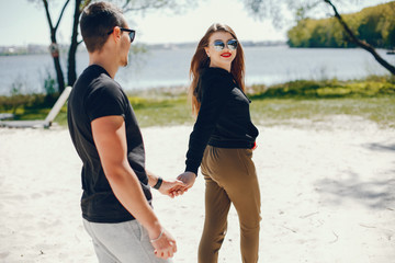 A stylish and bright love couple walks on the sunny beach