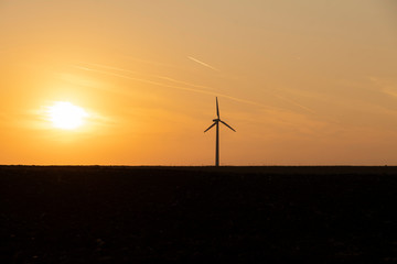 Obraz premium Wind turbine against sunset background
