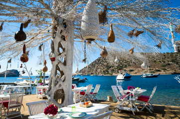 Informal beachside seating with decorative tree in the scenic tourist village of Gümüslük near Bodrum, Turkey