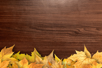 Obraz premium Autumn leaves over wooden background with copy space