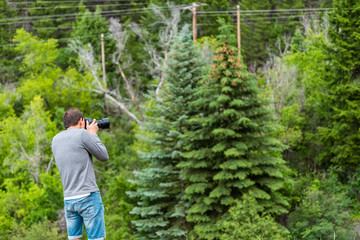 Man taking pictures with camera in Redstone, Colorado during summer with pine tree forest