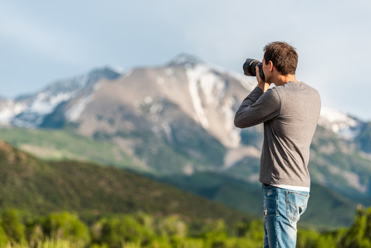 Closeup of man taking pictures of mt Sopris mountain in Carbondale, Colorado town view with snow mountain peak and sky in summer during sunset