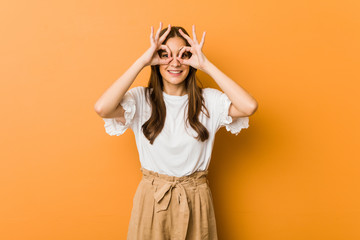 Young caucasian woman showing okay sign over eyes