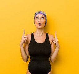 Young swimmer caucasian woman pointing upside with opened mouth.