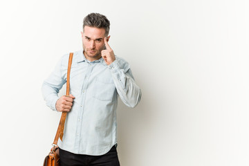 Young handsome business man pointing temple with finger, thinking, focused on a task.