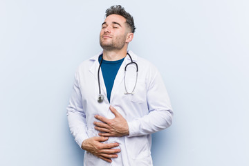 Fototapeta premium Young handsome doctor man touches tummy, smiles gently, eating and satisfaction concept.