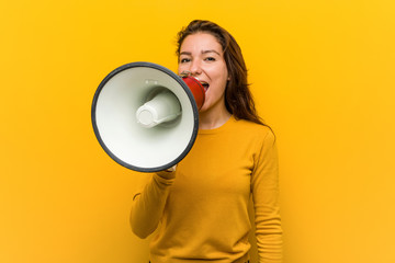 Young european woman holding a megaphone shouting excited to front.
