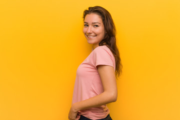 Obraz premium Young european woman isolated over yellow background looks aside smiling, cheerful and pleasant.