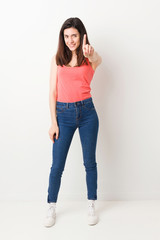 Full body young woman on white background showing number one with finger.