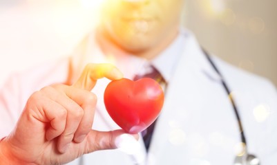 Young man doctor holding red heart
