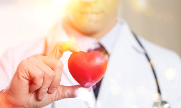 Young man doctor holding red heart