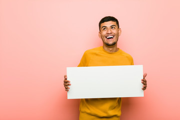 Young hispanic man holding a placard