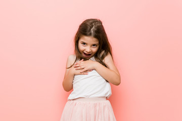 Little girl wearing a princess look laughing keeping hands on heart, concept of happiness.