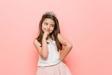 Little girl wearing a princess look smiling happy and confident, touching chin with hand.