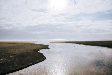 River flowing into the ocean with sun reflecting off the water