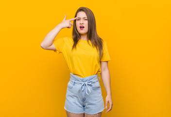 Young woman teenager wearing a yellow shirt showing a disappointment gesture with forefinger.