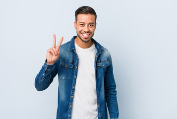 Young handsome filipino man showing victory sign and smiling broadly.