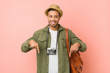 Young filipino traveler man points down with fingers, positive feeling. © Asier