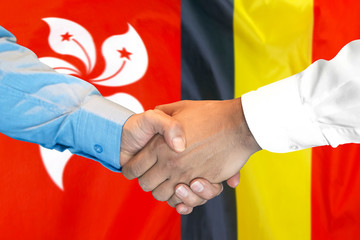 Handshake on Belgium and Hong Kong flag background.