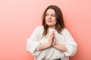 Fototapeta premium Young caucasian curvy woman standing against pink background