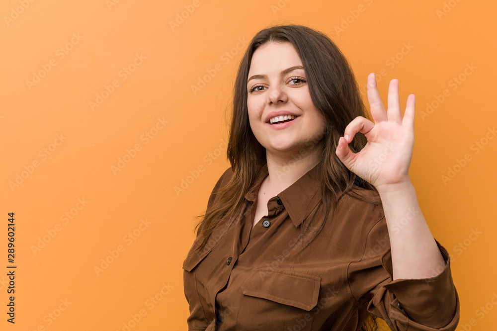 Wall mural Young curvy russian woman cheerful and confident showing ok gesture.