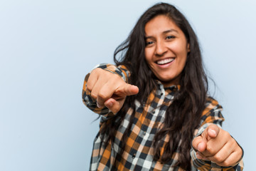 Young cool indian woman cheerful smiles pointing to front.