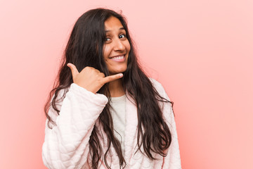 Young indian woman wearing pajama showing a mobile phone call gesture with fingers.