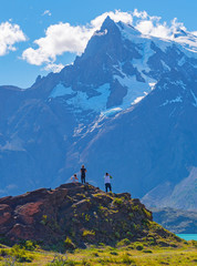 Vertical photograph of tourists looking upon the Pehoe Lake and the majestic peaks of Cuernos and Torres del Paine inside Torres del Paine national park near Puerto Natales, Patagonia, Chile.