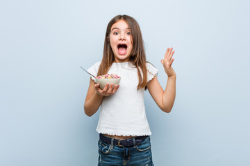 Little caucasian girl holding a cereal bowl celebrating a victory or success