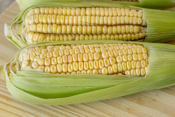 Closeup of raw corn cobs with straw over wood