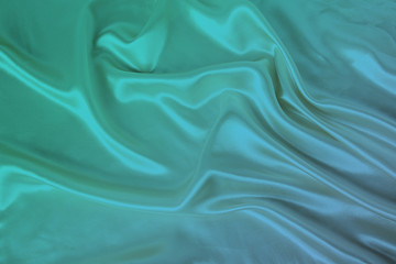 soft folds on delicate green shiny silk, luxury concept, background for the designer, horizontal, close-up, copy space
