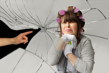 middle-aged woman, a housewife in curlers, with an unhappy expression on her face rests on the mop with both hands, the male hand points at her accusingly at the background of broken glass with cracks