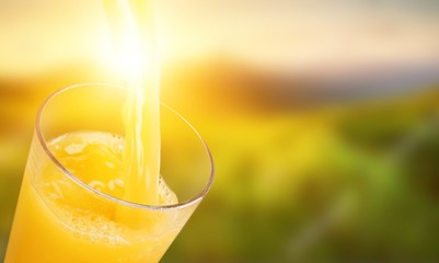 Orange juice glass on green blurred garden background, bokeh