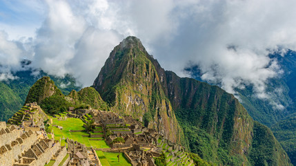 Panoramic landscape of the Machu Picchu Inca ruin coming out of the fog, Cusco Region, Peru.