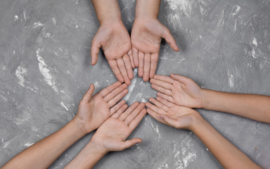 children's hands together in a circle on gray background, top view. 