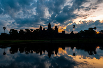 Silhouette reflection of the towers of Angkor Wat and sugar palm trees in a man made lake at sunrise near Siem Reap, Cambodia.