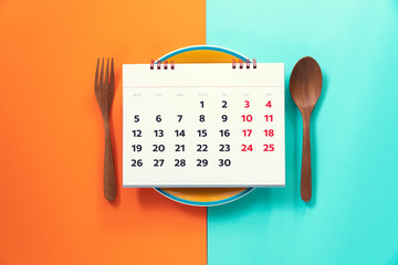 Food diary or food daily calendar, dish spoon and fork on the color table background, health concept