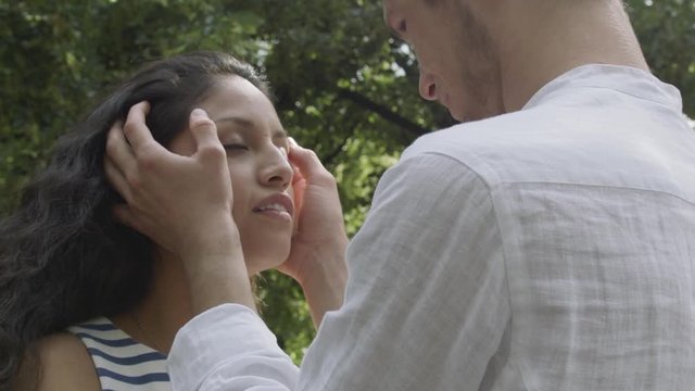 A young man touching his girlfriends face in a park.