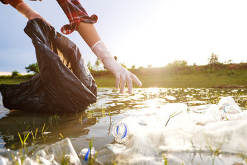 Young volunteers with garbage bags cleaning area on the lake , volunteer concept. Environmental...
