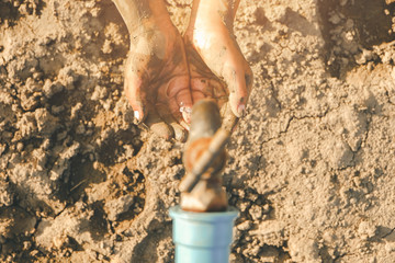 Sad a boy sitting on Crack dried soil background, open metal old tap on hot and dry empty land. Affected of global warming made climate change. Water shortage and drought concept.