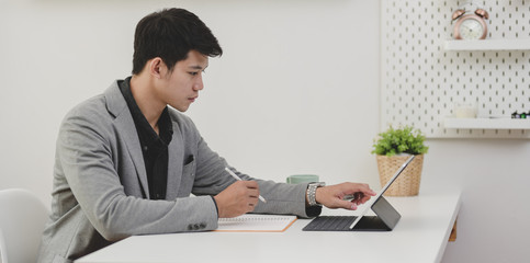 Fototapeta premium Young professional businessman working on his current marketing plan while writing on notebook