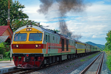 Obraz premium Locomotive Train Speeding up the engine resulting in black smoke after transporting passengers in Railway Station of Thailand. 